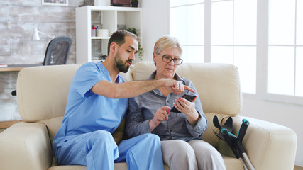 Male doctor teaching senior woman how to use her phone