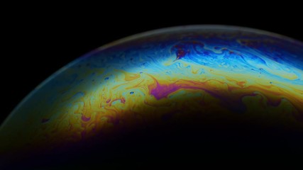 multicolored rainbow iris of soap bubble. fantastic colorful planet on black background. abstract mu