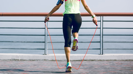 Poster - Young fitness woman jumping rope at seaside