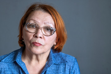 Portret of serious senior woman in glasses looking in the camera