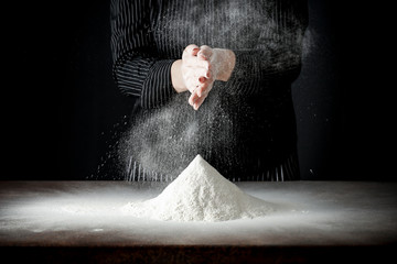 Poster - hands with flour working in the kitchen on the wooden table splash