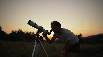 Wall Mural - astronomer with a telescope watching at the stars and moon.