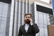 © Volodymyr - Businessman talking on the phone in financial district. Portrait of a Young urban professional man using smart phone over office building. Business man talking on his smartphone outdoors. Technology.