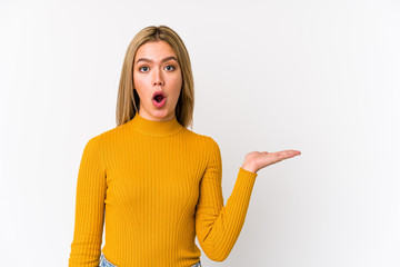 Young blonde caucasian woman isolated impressed holding copy space on palm.