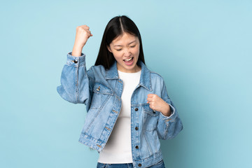 Wall Mural - Young asian woman isolated on background celebrating a victory