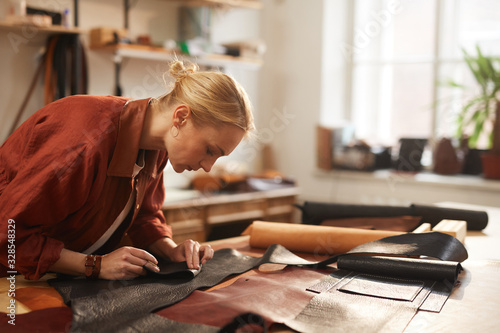 Cuadros en Lienzo Horizontal shot of young Caucasian woman preparing leather materials for new cra