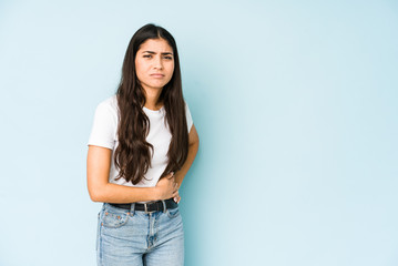 Wall Mural - Young indian woman on blue background having a liver pain, stomach ache.