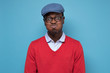 © Viktor Koldunov - Young african man in red sweater and blue hat puffing cheeks holding breath