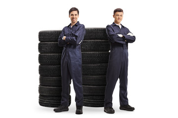 Wall Mural - Young male auto mechanic workers posing with piles of tires