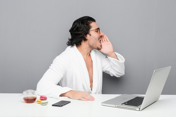 Young handsome man working after a shower shouting and holding palm near opened mouth.