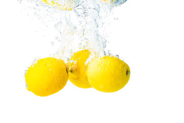 Wall Mural - Lemons splash into water and sinking on white background.