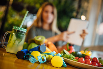 Fresh healthy food with dumbbells, jump rope, and excercise equipment on wooden background, dieting, fitness and active healthy lifestyles concept