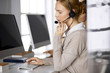 © rogerphoto - Businesswoman talking by headset while sitting in office. Call center and diverse people group in business