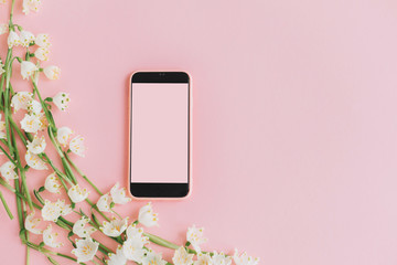 Pink smartphone with empty screen and white spring flowers on pink flat lay. Floral tender border and phone template with copy space. Stylish girly greeting card. Happy women's day or mothers day