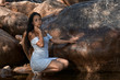 © Trepalio - Joven morena de pelo posando junto a las rocas en la montaña con los pies en el agua.