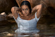 © Trepalio - Joven morena de pelo posando junto a las rocas en la montaña con el cuerpo dentro del agua.