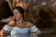 © Trepalio - Joven morena de pelo posando junto a las rocas en la montaña con el cuerpo dentro del agua.