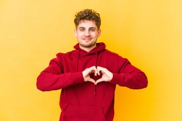  smiling and showing a heart shape with hands.