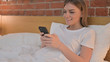 © stockbakers - Young Woman Using Smartphone in Bed