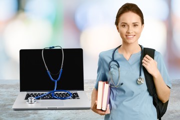 Poster - Modern laptop computer with stethoscope and beautiful doctor