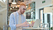 © stockbakers - Redhead Man having Loss on Laptop in Cafe
