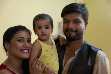 Happy Indian Bengali family with smiling mom, dad and baby. Indian lifestyle