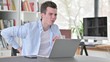 © stockbakers - Young Man with Back Pain Working on Laptop