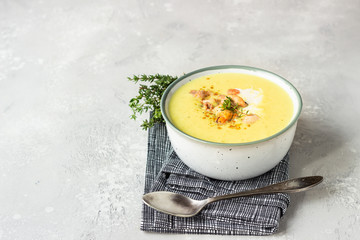 Thick milky chowder soup with seafood served with sour cream, thyme and pepper. Light grey stone background. 