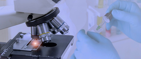Wall Mural - laboratory concept; close up of microscope with a blurred picture of the scientist is researching in