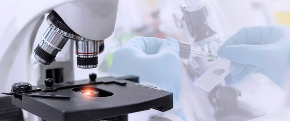 Wall Mural - laboratory concept; close up of microscope with a blurred picture of the scientist is researching in
