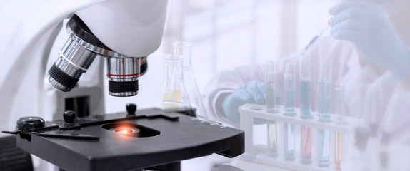 Wall Mural - laboratory concept; close up of microscope with a blurred picture of the scientist is researching in
