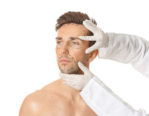 Wall Mural - Plastic surgeon touching face of young man on white background