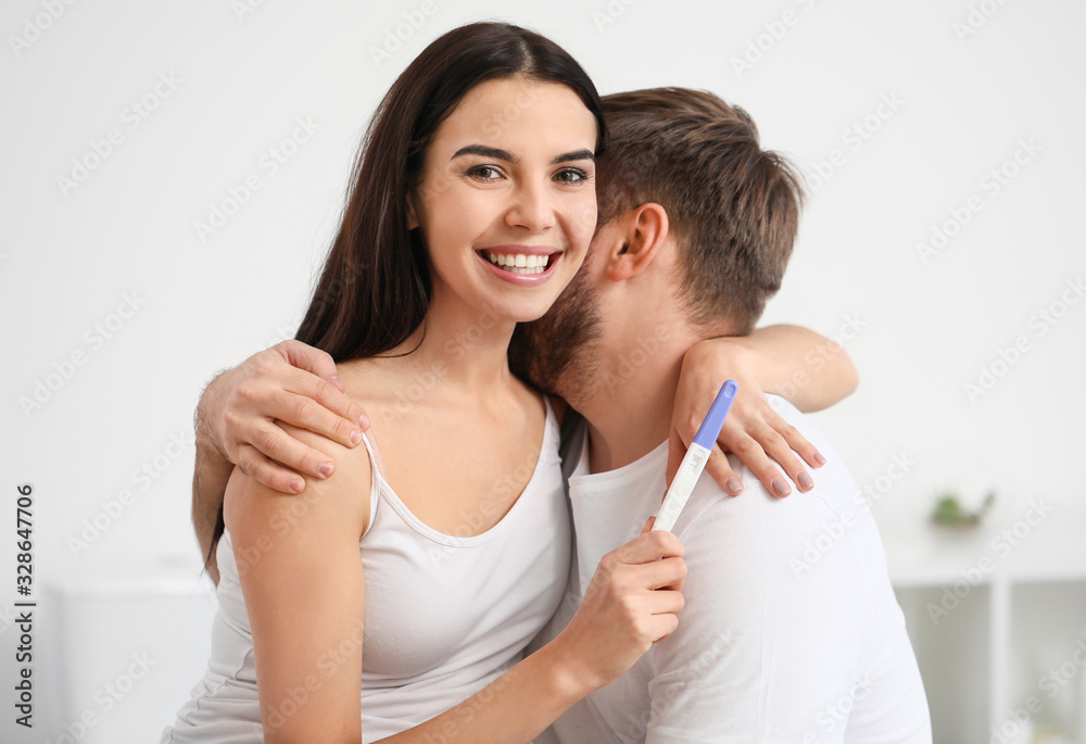 Happy young couple with pregnancy test in bathroom