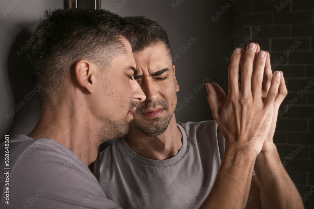 Depressed young man near mirror