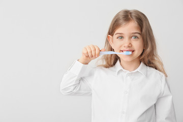 Wall Mural - Cute little girl with toothbrush on white background