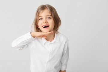 Wall Mural - Happy little girl with healthy teeth on light background