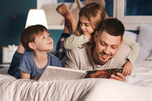 Father And His Little Children Reading Bedtime Story At Home