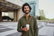 © StratfordProductions - Portrait of handsome young businessman holding coffee cup standing outdoor