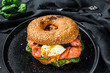 Smoked salmon bagel toasts with soft cheese, spinach and egg. Black background. Top view