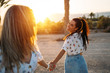 © ManuPadilla - A beautiful and smiling pair of women holding each other's hands as they enjoy their beach vacation - Vacation concept - Close-up