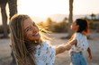 © ManuPadilla - Two beautiful and smiling women enjoying their vacation on the beach with the sun behind them - Vacation concept - Close-up