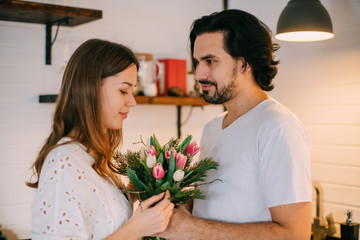 International Women's Day. Young couple in the morning in the kitchen at home