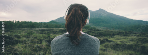 Fotografía Woman in headphones listening music in nature and at the mountain