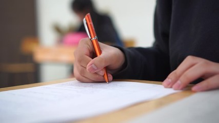 Wall Mural - exam classroom of students group hands holding fill in carbon paper sheet or test papers on wood des