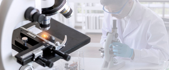 Wall Mural - laboratory concept; close up of microscope with a blurred picture of the scientist is researching in