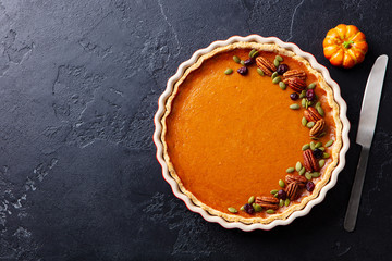 Wall Mural - Pumpkin pie in baking dish. Black slate background. Copy space. Top view.