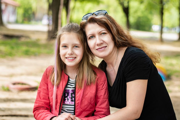 Wall Mural - Middle-aged woman hugs her teenage daughter and they smile and relax together after serious talk about teenage issues