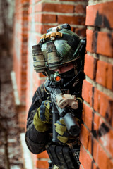 Wall Mural - Closeup military man in black camouflage uniform aims aiming from around the corner.