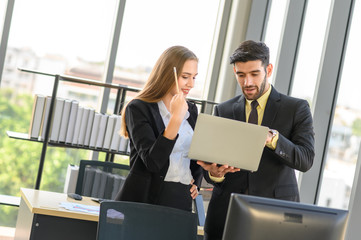 Young business partners discussing about works with laptop. Businessman and businesswoman in office.