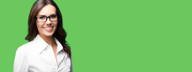 Happy smiling brunette businesswoman in glasses, with blank copy space area for slogan or text. Success in business concept. Green color background.